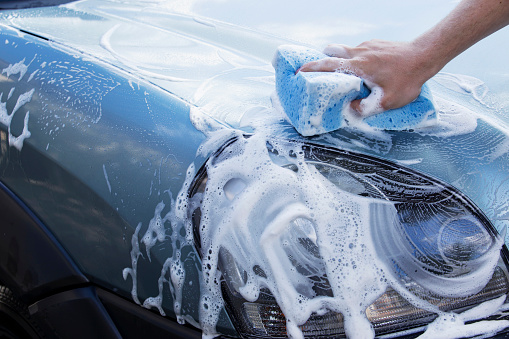 the turquoise car is washing in soap suds