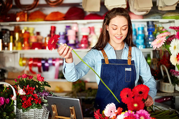 Florist arranging fresh Gerbera daisies at checkout counter