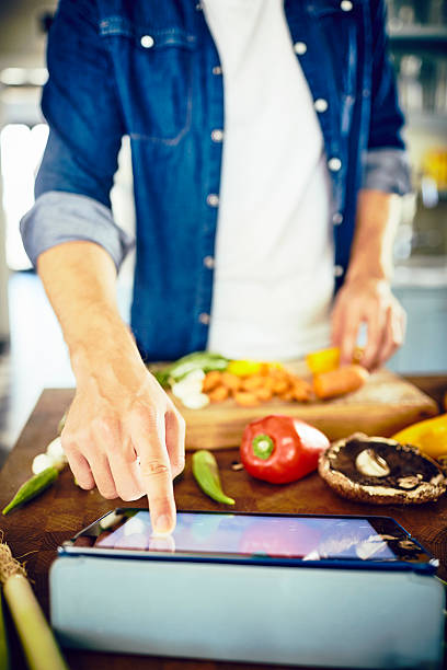 istock Man touching screen of digital tablet while preparing food 576578882