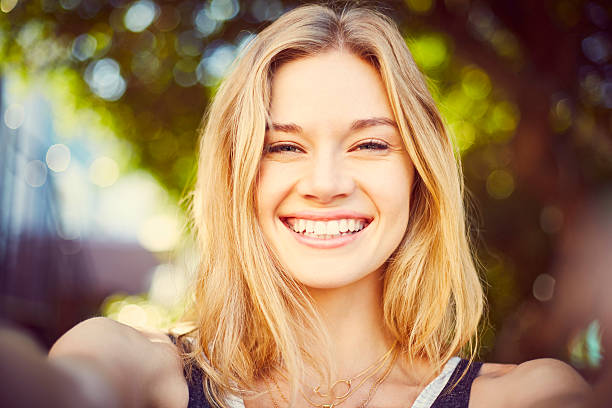 Point of view of beautiful blond woman taking selfie Point of view portrait of beautiful blond woman taking selfie. Attractive female is smiling. Close-up of lady is outdoors on city street. medium length hair stock pictures, royalty-free photos & images