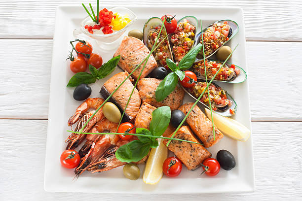 Grilled seafood variety on white plate with sauce
