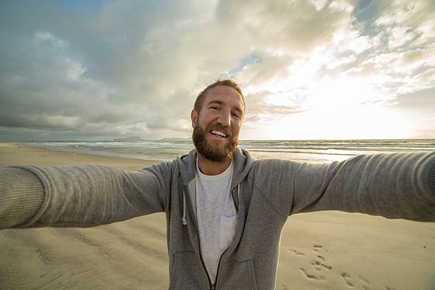 istock Hipster man takes selfie on beach at sunset 576582198