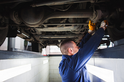 Suspension system of SUV restoration in garage. Mechanic recovering car wheel under vehicle