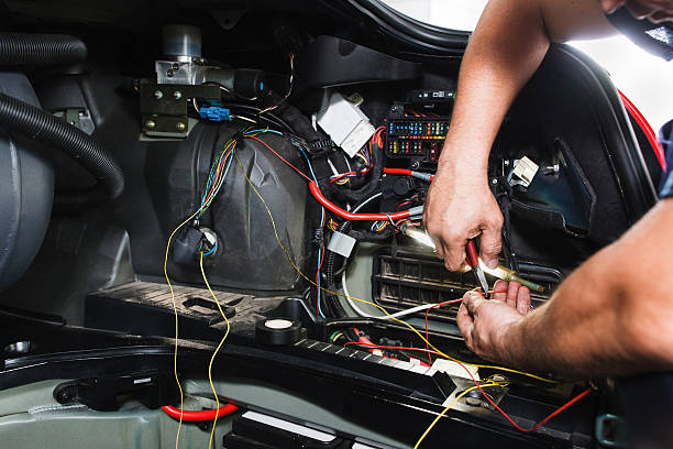 Electrician works with electric block in car Electrician works with electric block in car. Close-up of automobile inside under raised hood. Service man hands working with cables of auto amperage stock pictures, royalty-free photos & images