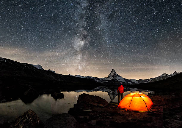 Loneley Camper under Milky Way at Matterhorn An illuminated tent under Milky Way at Matterhorn in Switzerland long exposure photos stock pictures, royalty-free photos & images