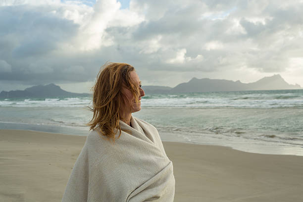 istock Woman on beach contemplating seascape 576584098
