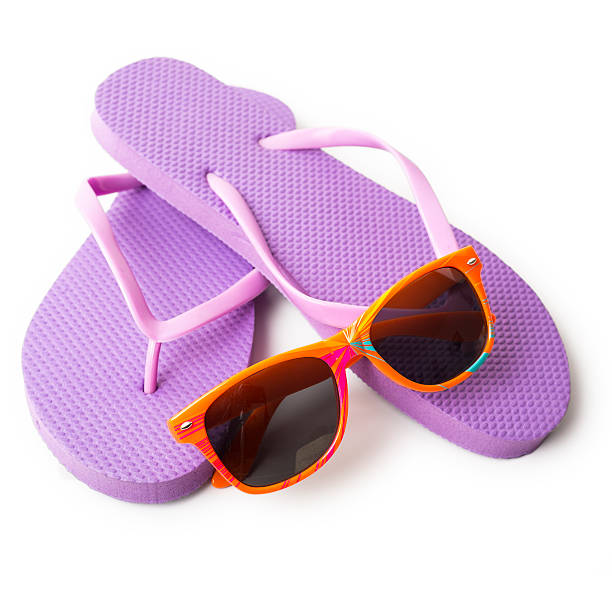 istock Purple beach sandals with orange sunglasses isolated on white background 576587184
