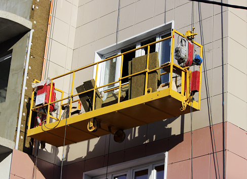 construction suspended yellow cradle without workers on a newly built high-rise building in Moscow