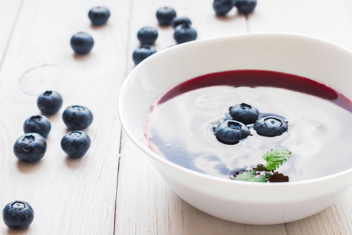 blueberry soup on wooden white background, close-up