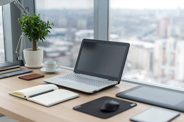 istock Sideview of office desktop with blank laptop and various tools. 576591784