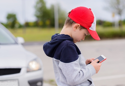 Niño jugando juegos móviles en el teléfono inteligente en la calle photo