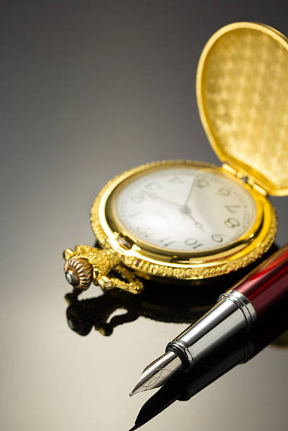 istock pocket watch and ink pen on black 576594848