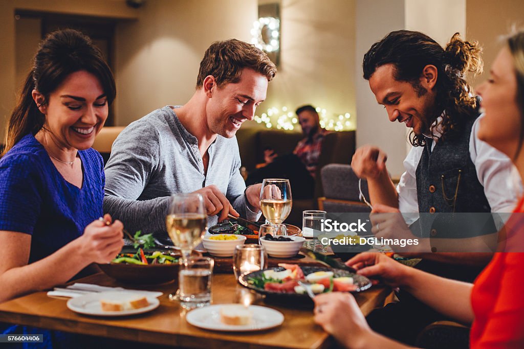 Double Date Dining Group of friends enjoying an evening meal with wine at a restaurant. Restaurant Stock Photo