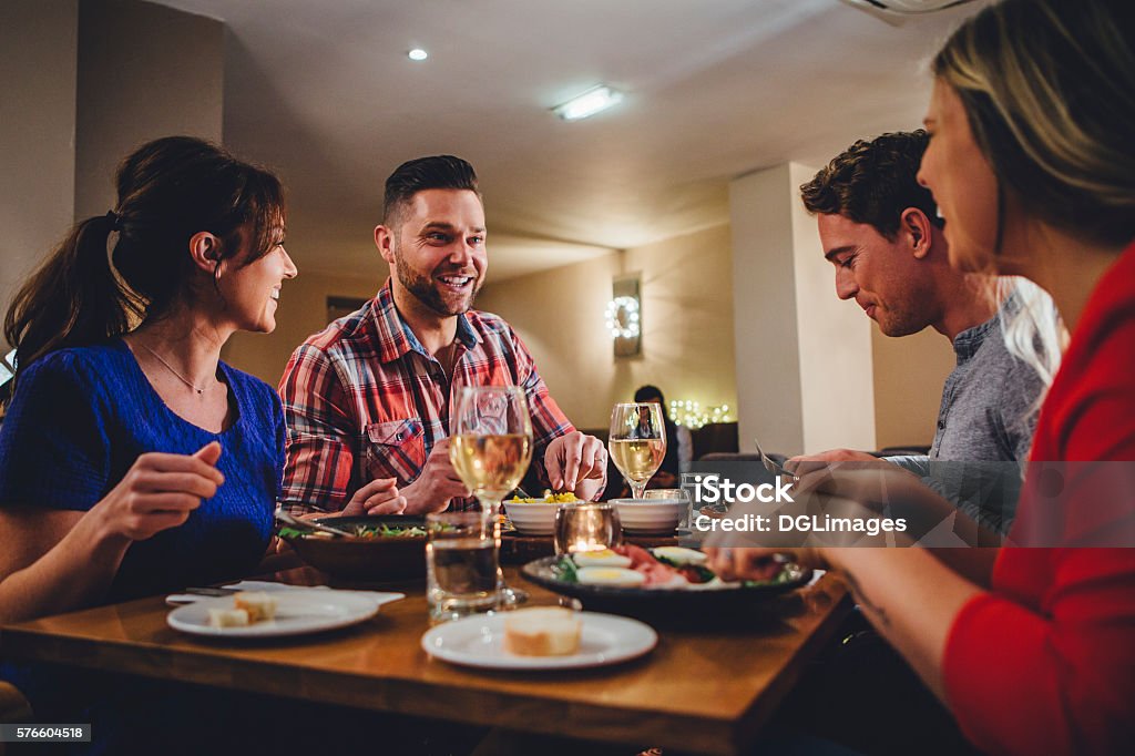 Double Date Dining Group of friends enjoying an evening meal with wine at a restaurant. Dining Stock Photo