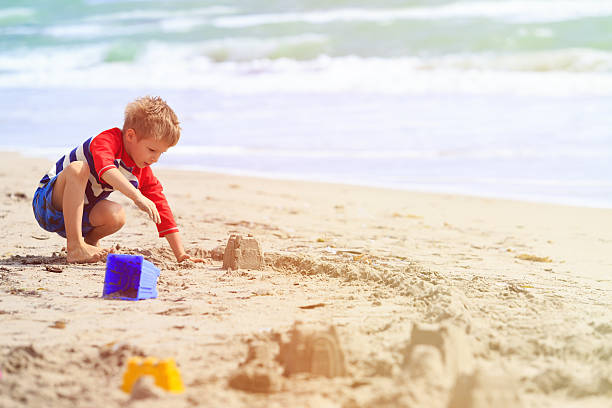 istock little boy play with sand on summer beach 576711464