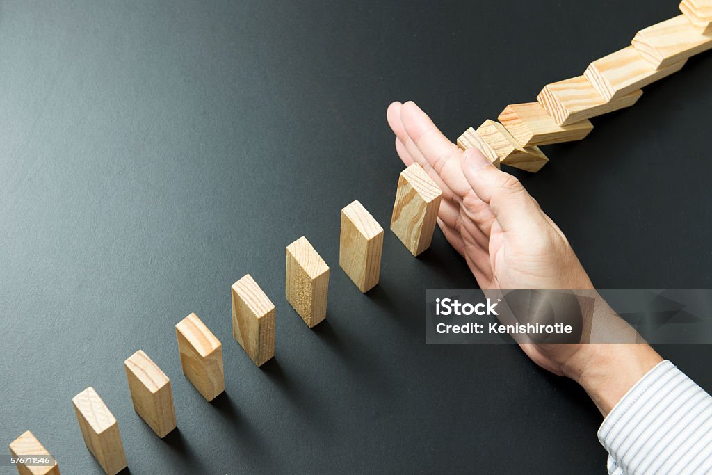 Business solution concept Solution concept with hand stopping wooden blocks from falling in the line of domino Crisis Stock Photo