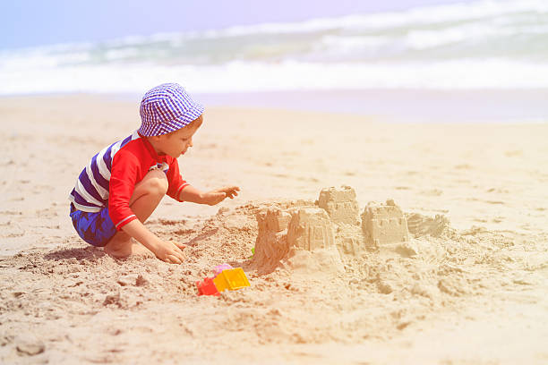istock little boy play with sand on summer beach 576711738