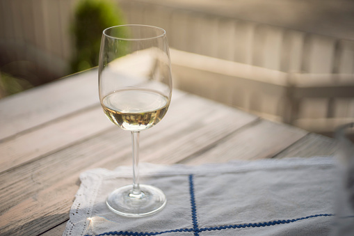 Glass of white wine on the wooden table and white - blue table cloth