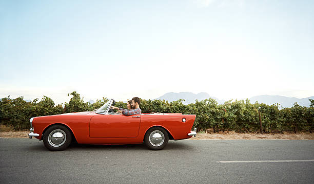 Shot of a young couple out on a road trip in a vintage convertible