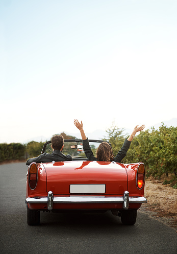 Shot of a young woman with her hands up while on a road trip with her girlfriend