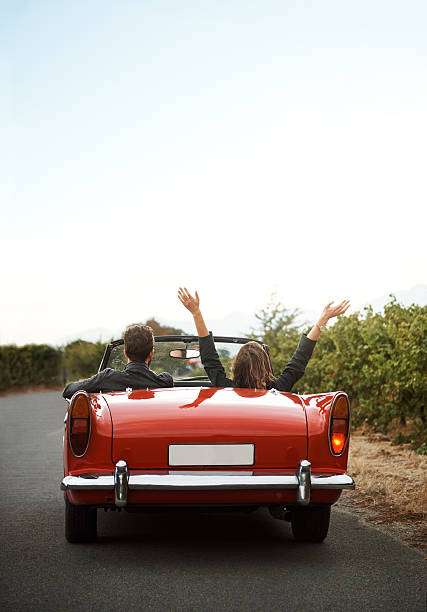 Go on a road trip with someone fun Shot of a young woman with her hands up while on a road trip with her girlfriend convertible stock pictures, royalty-free photos & images