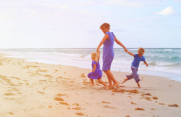istock mother and two kids play on beach 576715664