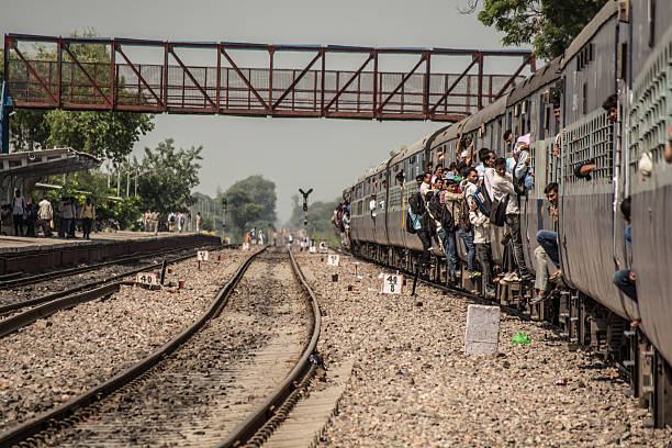 Passengers hanging off an overcrowded train. Delhi, India - August 24, 2015: Passengers hanging off an overcrowded train. india train stock pictures, royalty-free photos & images
