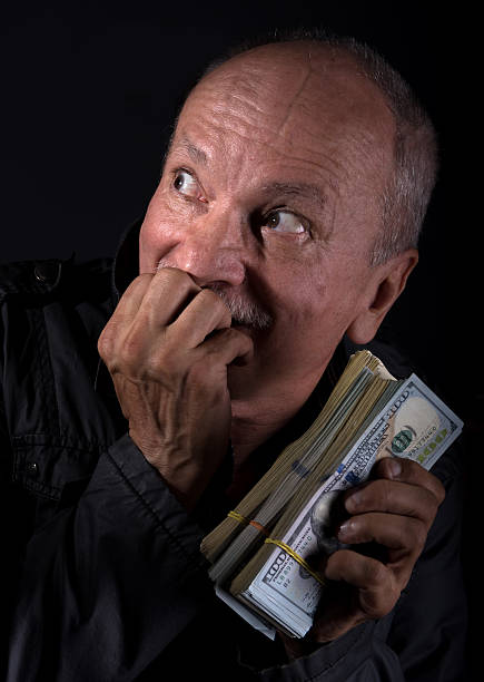 istock Sly senior man holding dollar bills 576721732