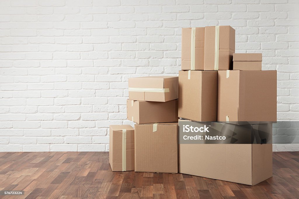 Moving in Moving in. Stack of cardboard boxes in the empty room with copy space Box - Container Stock Photo