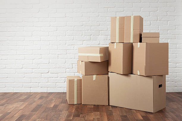 Moving in Moving in. Stack of cardboard boxes in the empty room with copy space cardboard box stock pictures, royalty-free photos & images