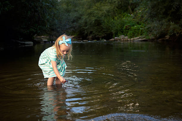 istock Adorable blond girl playing in river, exploration and education concept 576723468