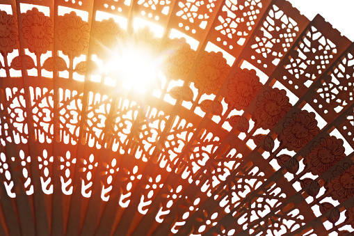 Sun shining through Japanese decorated wooden fan