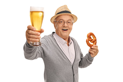 Mature man holding a pint of beer and a pretzel isolated on white background
