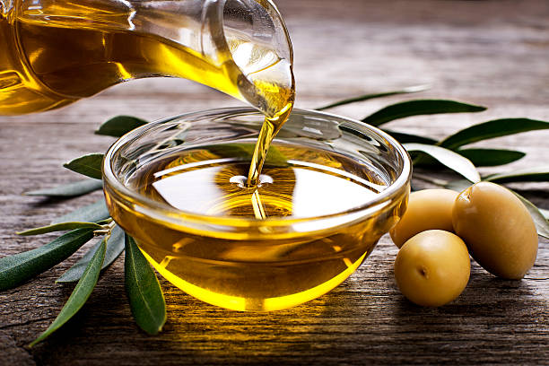 Olive oil Bottle pouring virgin olive oil in a bowl close up cooking oil photos stock pictures, royalty-free photos & images