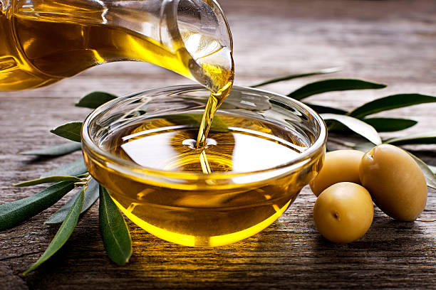 Olive oil Bottle pouring virgin olive oil in a bowl close up OLIVE OIL stock pictures, royalty-free photos & images