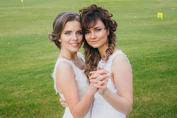Two beautiful brides dancing  on the green field of the golf club
