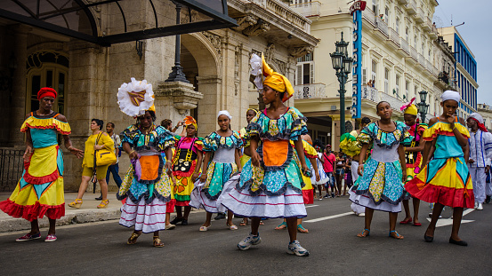 Havana, Cuba – June 9, 2016: Women in colorful costumes celebrate Havana Day by dancing in a parade along Paseo de Marti in the historic La Habana Vieja neighborhood.