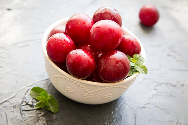 istock Delicious red plums in a wooden bowl, selective focus 576737740
