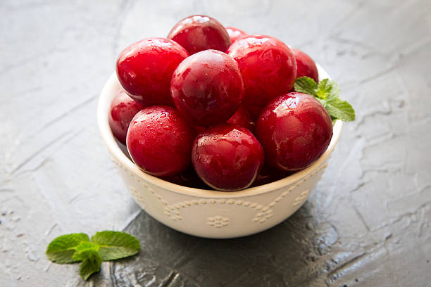 istock Delicious red plums in a wooden bowl, selective focus 576737950