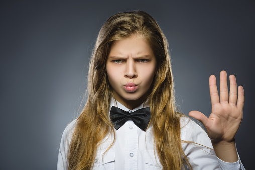 girl shows the stop arm isolated on gray background.