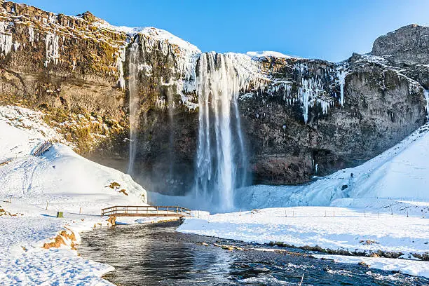 Waterfall Seljalandsfoss in winter, reflection in river. Iceland.