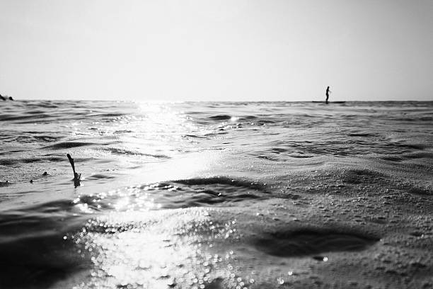 Shimmering Sea at Fistral beach with unrecognisable Paddle surfer.