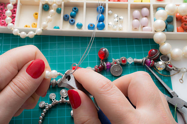 istock woman cuts with pliers loose thread strands from her bracelet 576743424