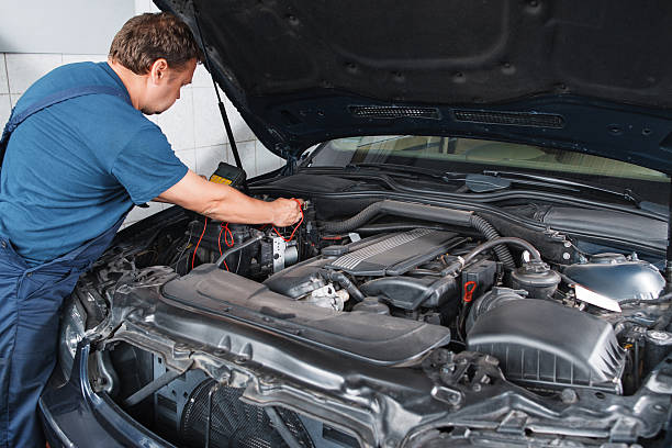 istock Electrician testing car with multimeter at garage 576746344