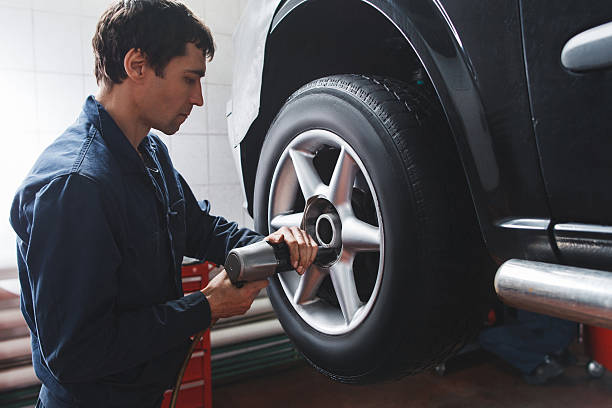 mecânico troca roda de carro em oficina de reparação de automóveis - tire car built structure surrogate - fotografias e filmes do acervo