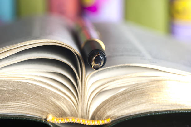 istock Close-up of open book and pen. 576746498
