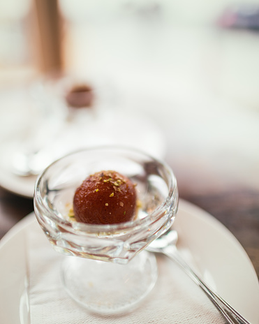 A close look at the Indian dessert called gulab jamun. Another one, out of focus can be seen in the background.