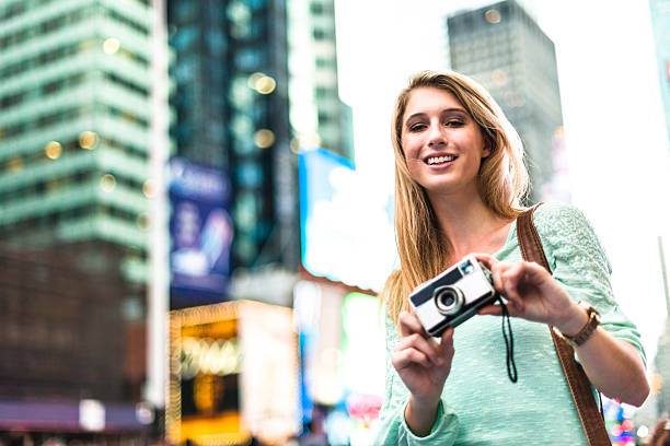 istock pretty woman smiling on times square with camera 576748422