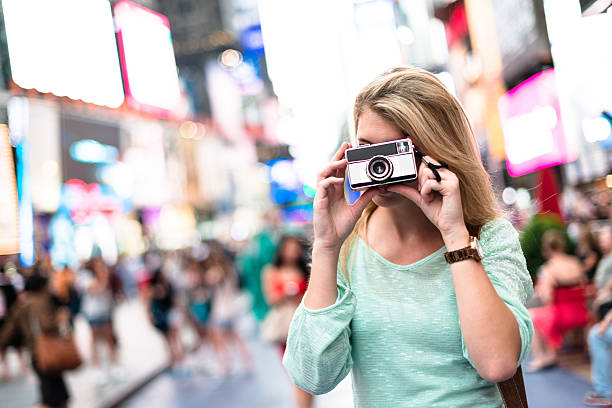 istock pretty woman smiling on times square with camera 576748518