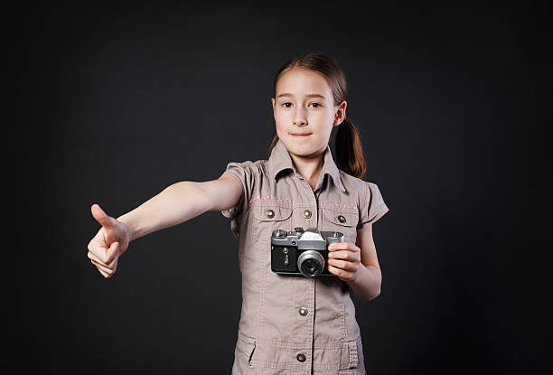 bambina con fotocamera vintage pollice in su su su su sfondo nero - fashionable studio shot indoors lifestyles foto e immagini stock